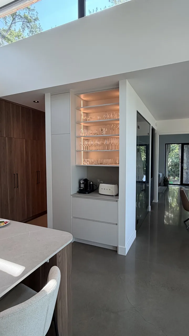 Bar intégré avec étagères en verre éclairées et comptoir en Silestone
