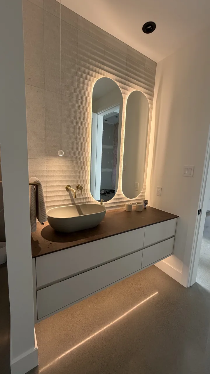 Salle d’eau avec vasque ovale et double miroir cintré rétroéclairé